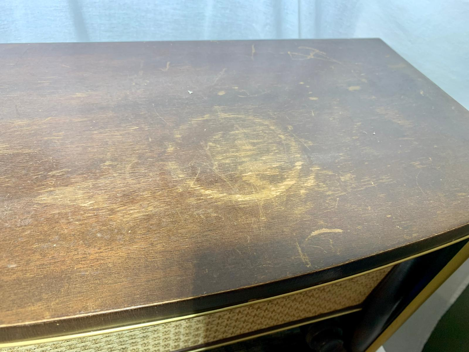 Water rings and worn varnish on the top of a vintage wooden radio cabinet